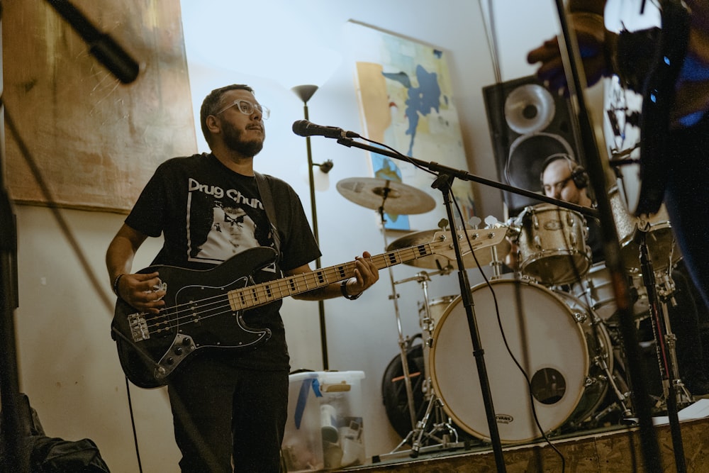 a man playing a bass guitar in front of a microphone