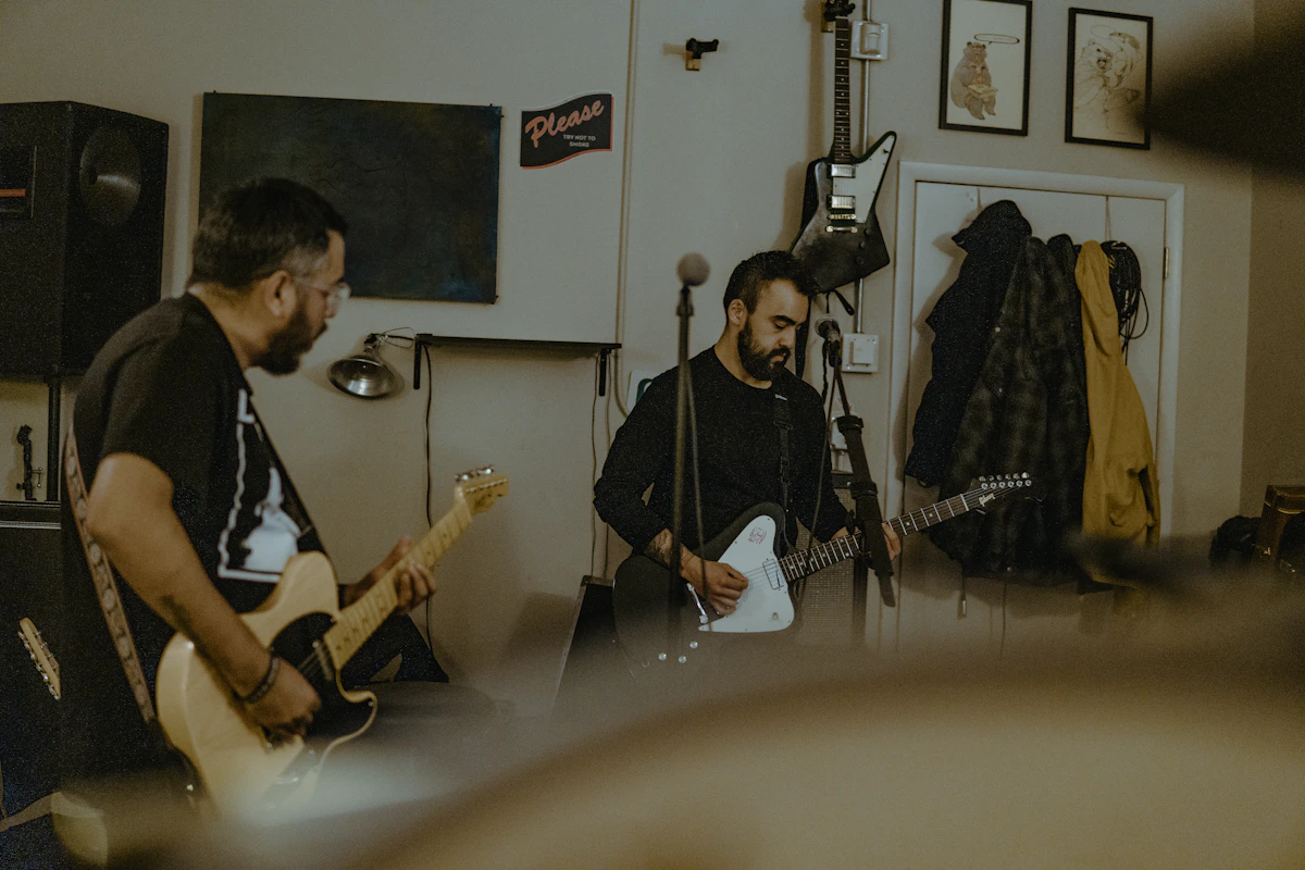 Several musicians are rehearsing in a room, playing guitars.