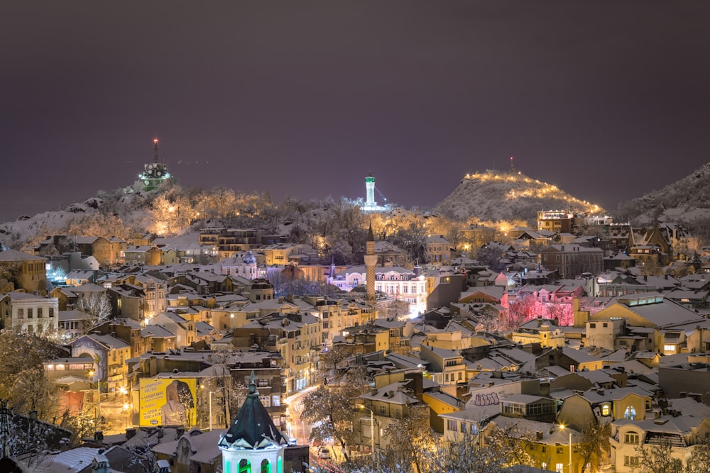 Una vista di una città di notte con una montagna innevata sullo sfondo