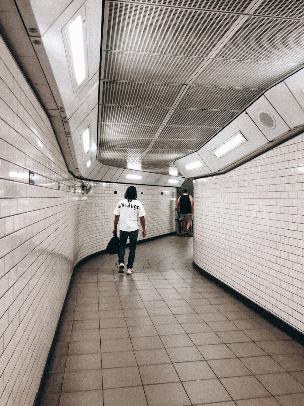 a person walking down a long hallway in a subway
