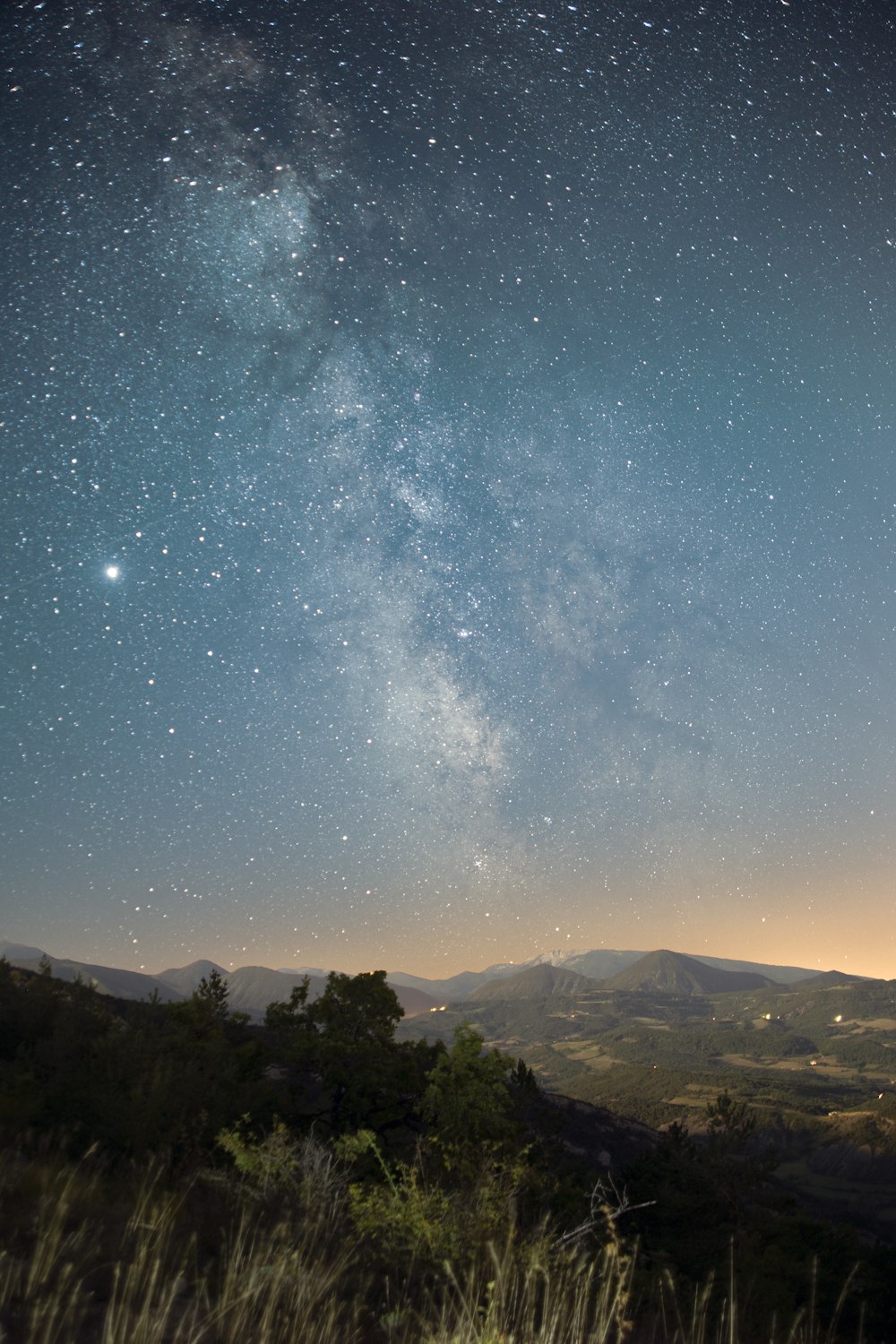 a view of the night sky from a hill