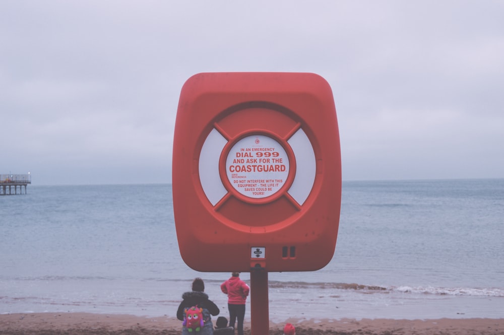 a life preserver on a beach with people standing around it