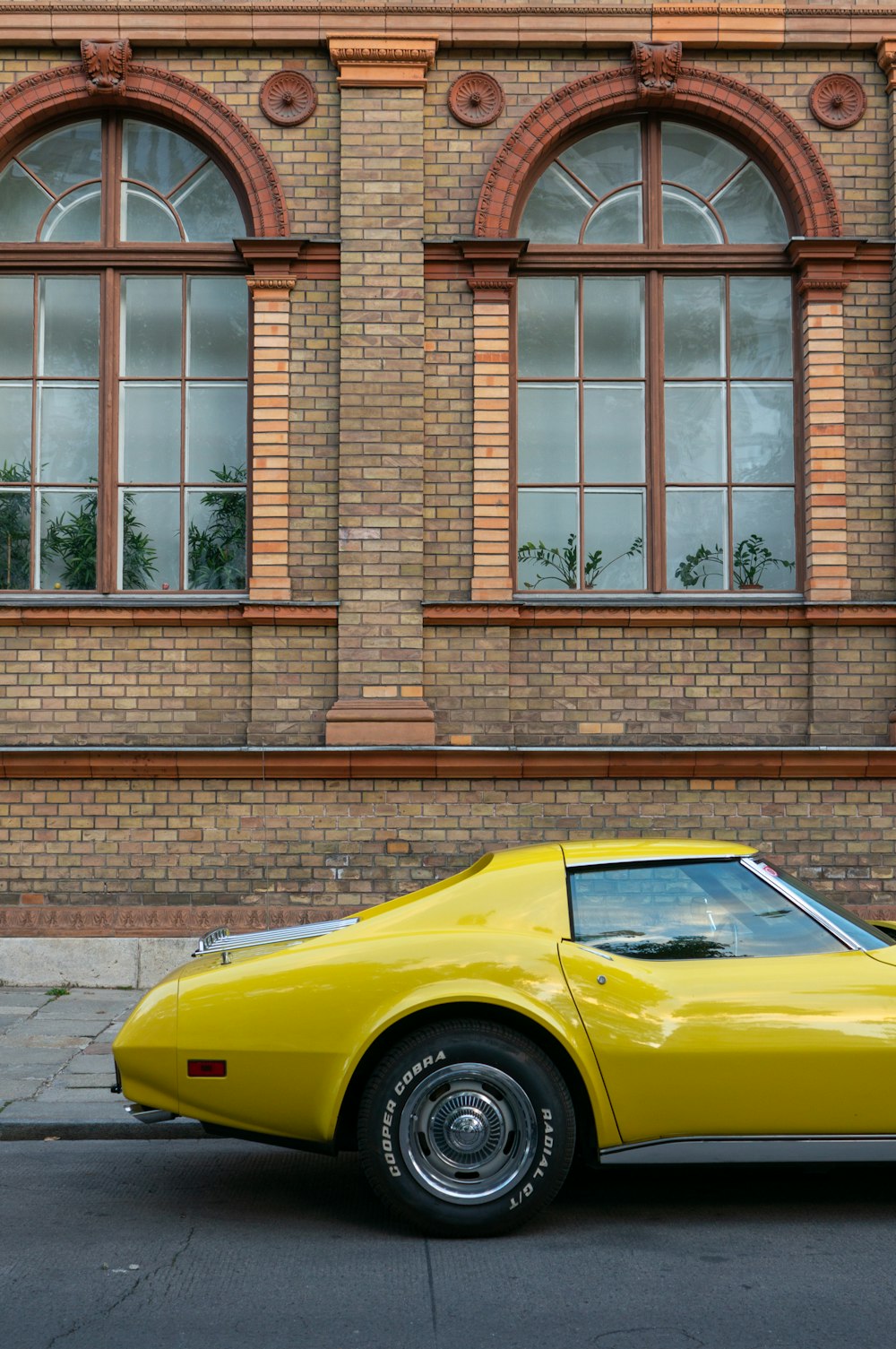 a yellow sports car parked in front of a brick building