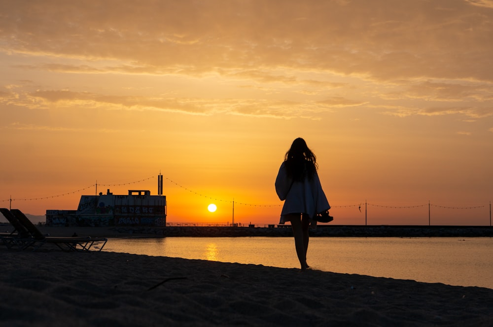 a woman standing on a beach at sunset