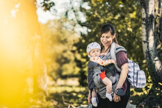 A parent effortlessly securing a structured baby carrier with padded straps while hiking outdoors.