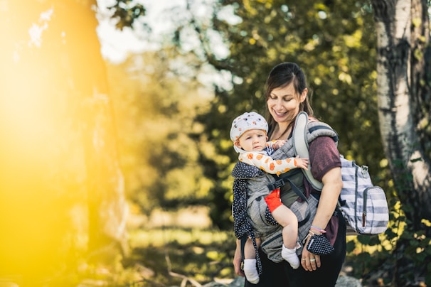 A happy parent comfortably carrying their baby in a soft, ergonomic carrier outdoors.