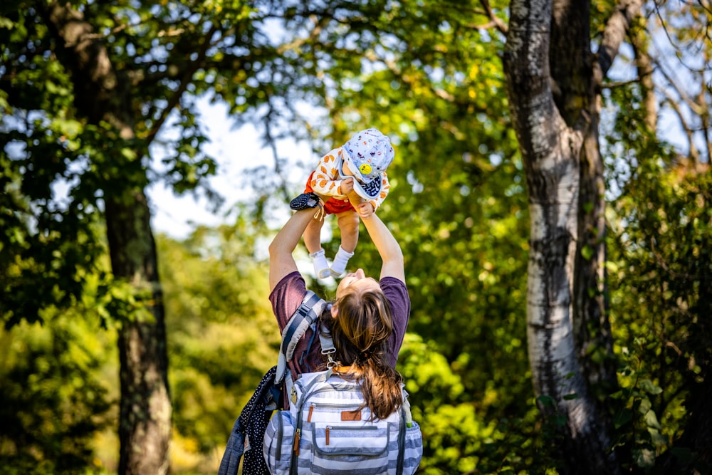 a woman holding a baby in her arms in the woods