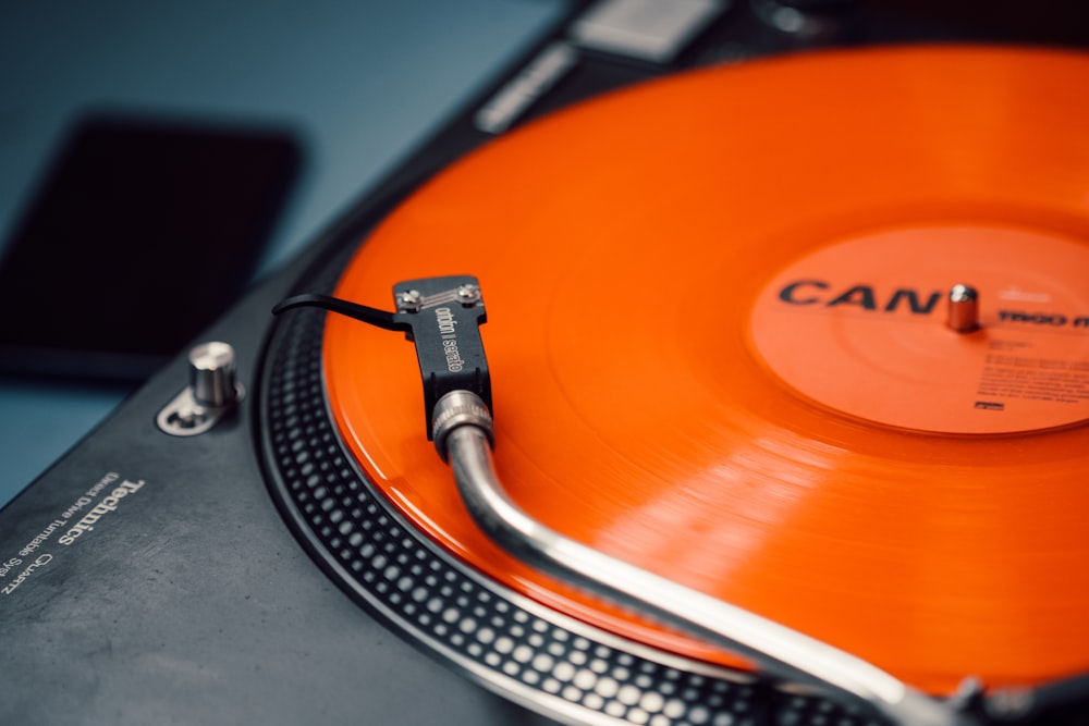 a turntable with an orange vinyl record on it