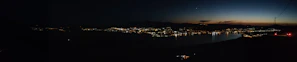 A panoramic view of a nighttime urban skyline with subtle silver and smoky white highlights.