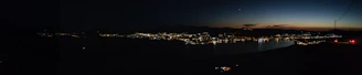 A panoramic view of a nighttime urban skyline with subtle silver and smoky white highlights.