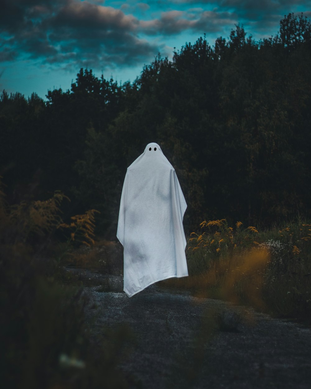 a white ghost standing in the middle of a forest