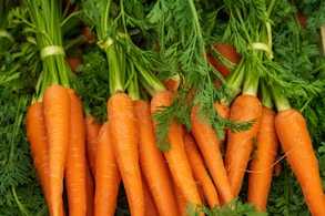 a pile of carrots with green tops and leaves
