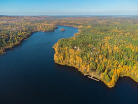 Aerial view of smaller lakes in autumn with private docks and forested shoreline.