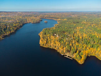 Aerial view of smaller lakes in autumn with private docks and forested shoreline.