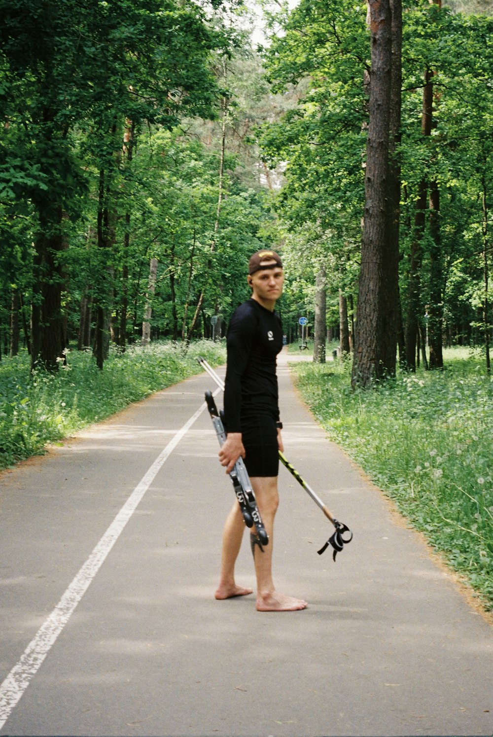 a man holding a pair of skis while standing on a road