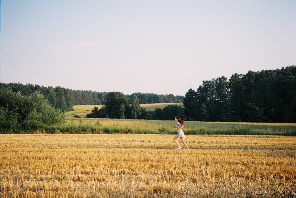 a woman running through a field of wheat