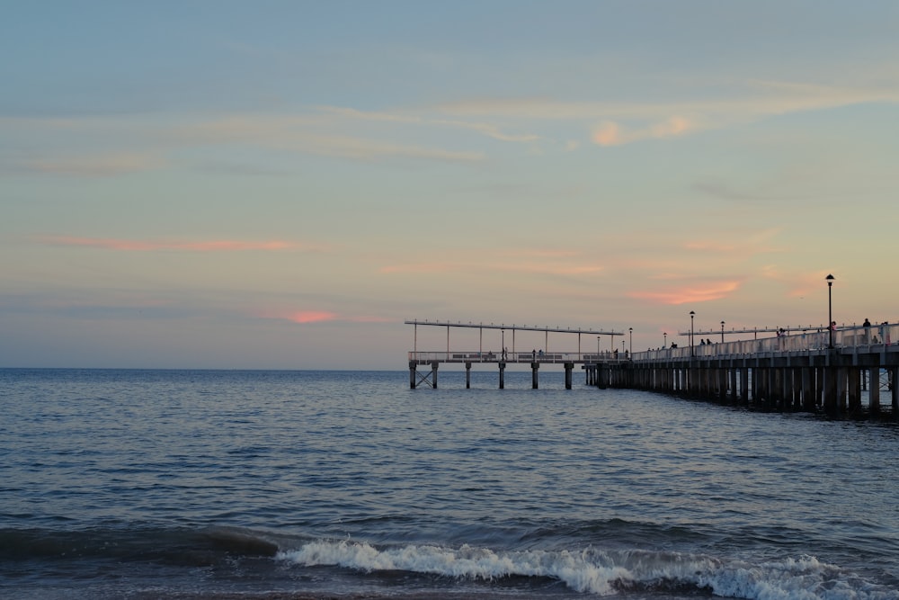 a pier on the ocean with a sunset in the background