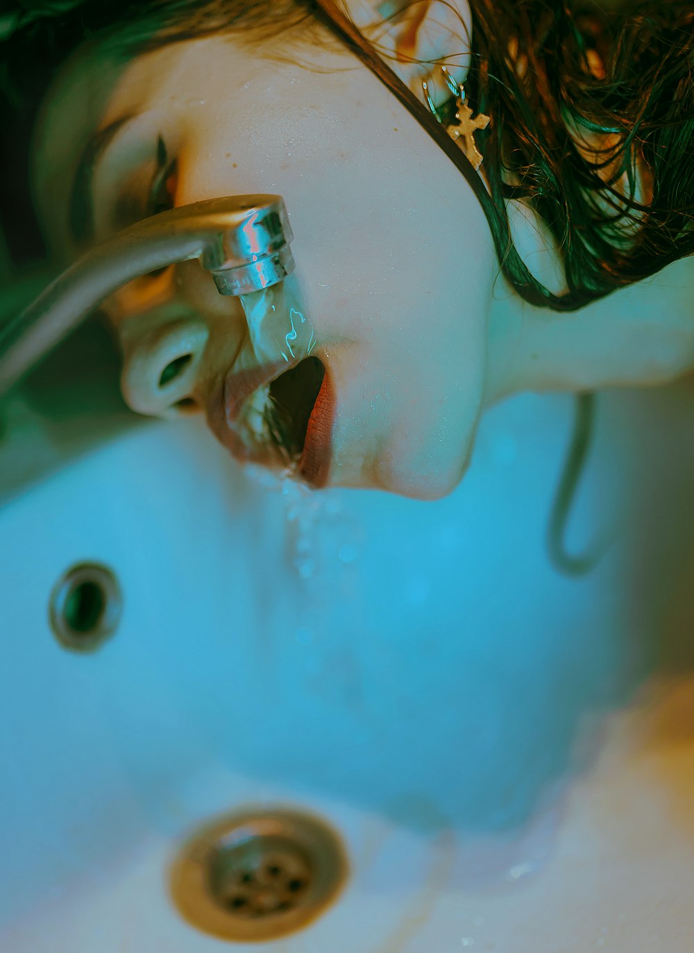 a woman drinking water from a faucet in a sink