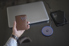 a person holding a wallet next to a laptop