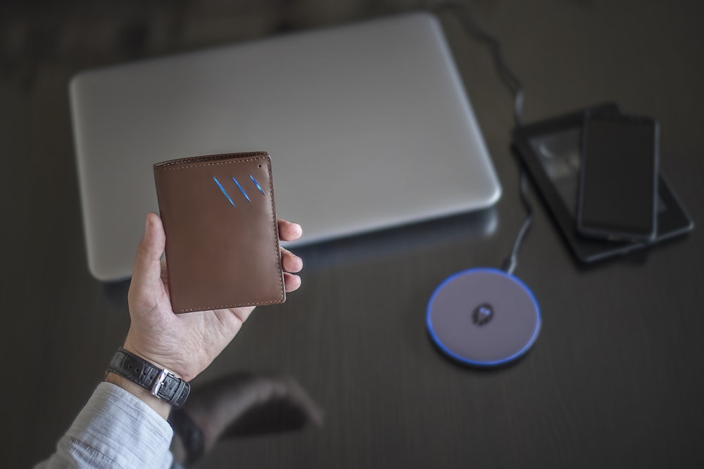 a person holding a wallet next to a laptop