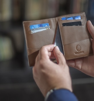 a person holding two wallets in their hands