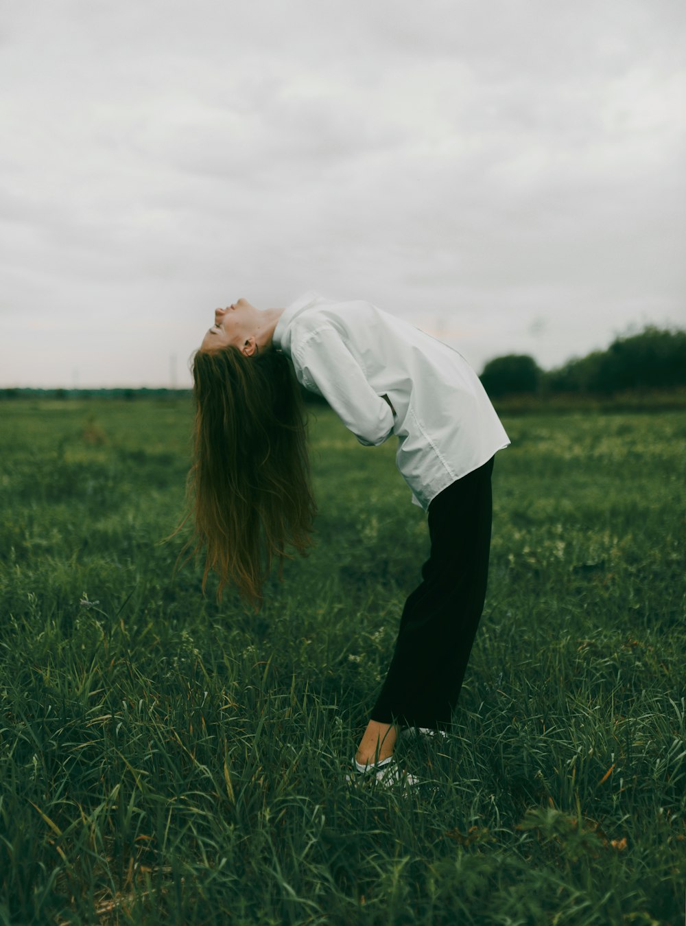 a woman with long hair standing in a field