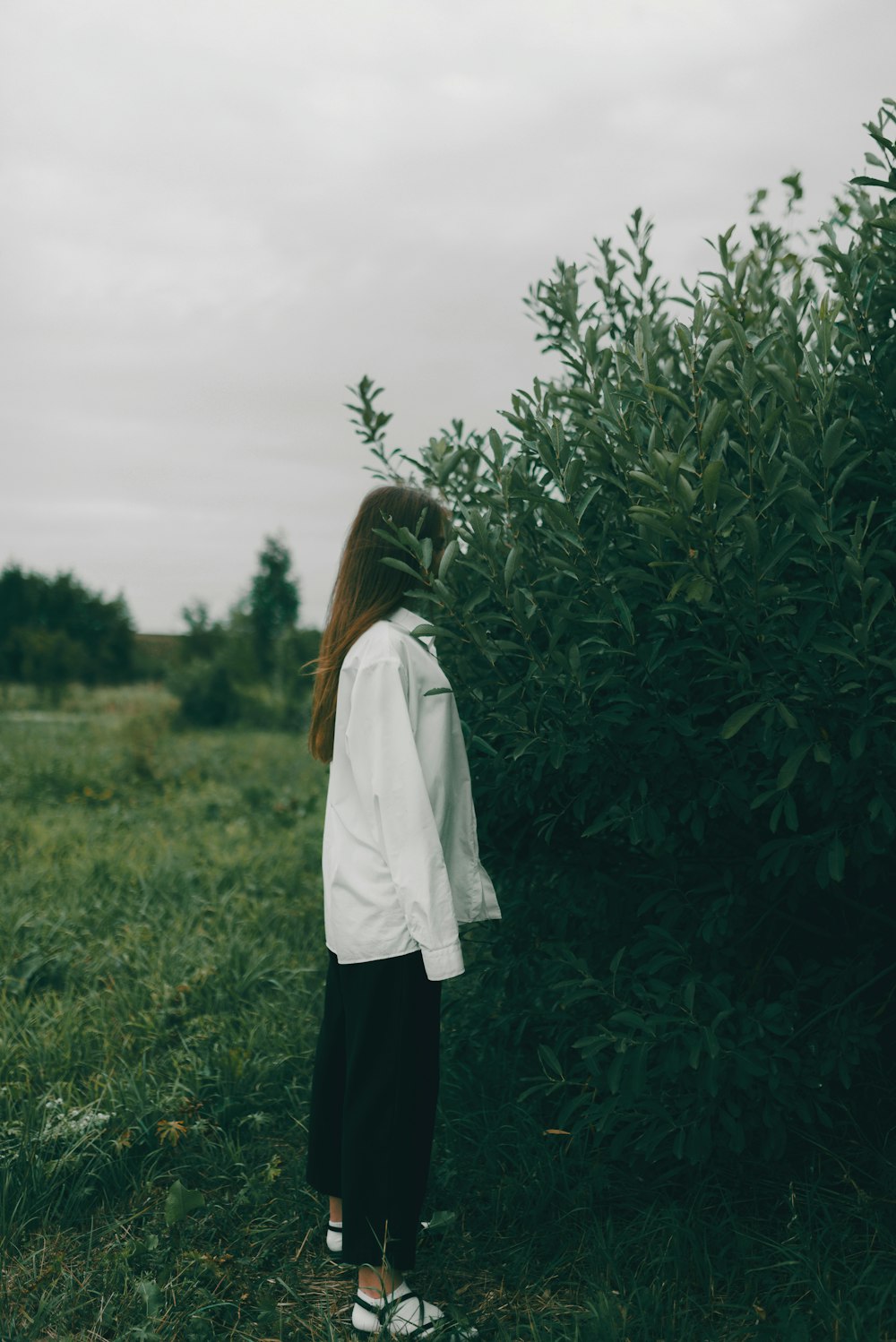 a woman standing in front of a bush