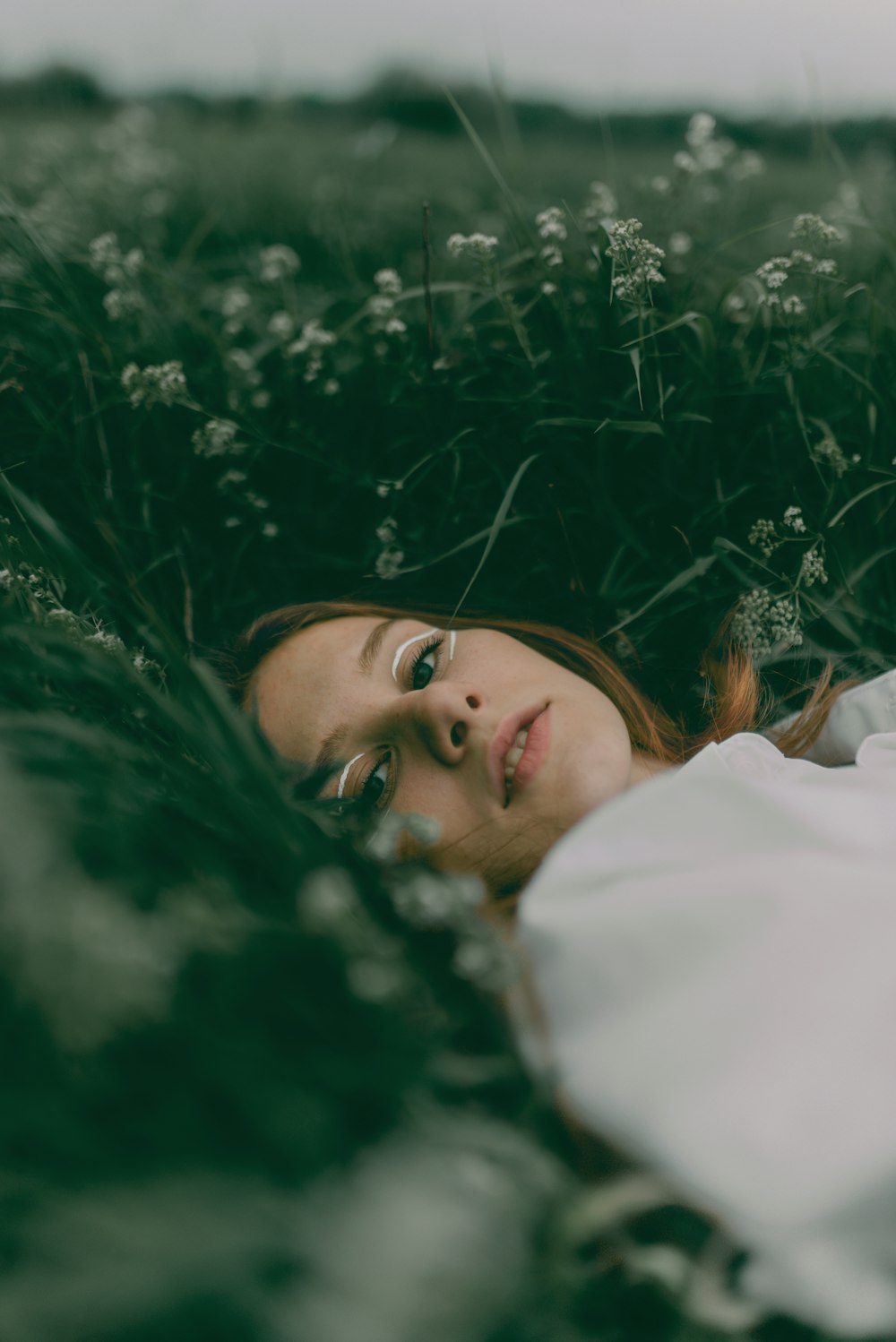 a woman laying in a field of tall grass