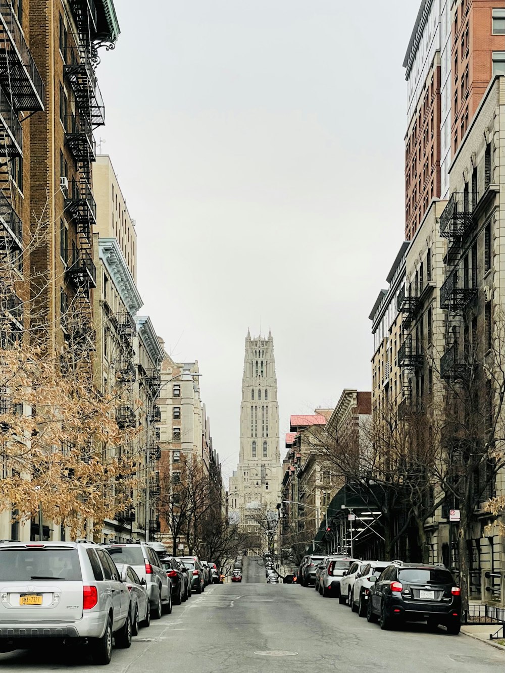 a city street lined with parked cars and tall buildings