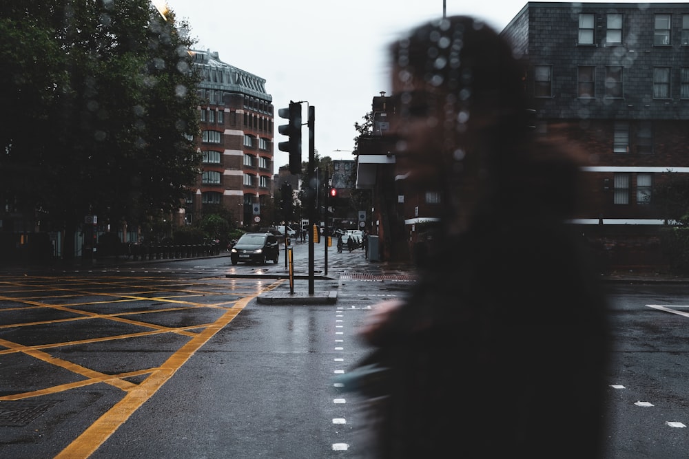 a woman walking down a street next to a traffic light