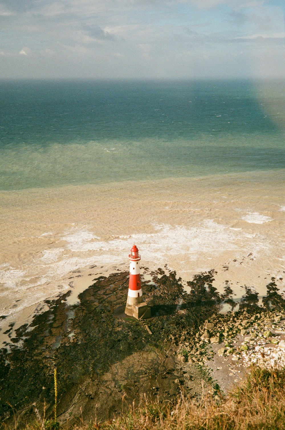 a red and white lighthouse sitting on top of a sandy beach