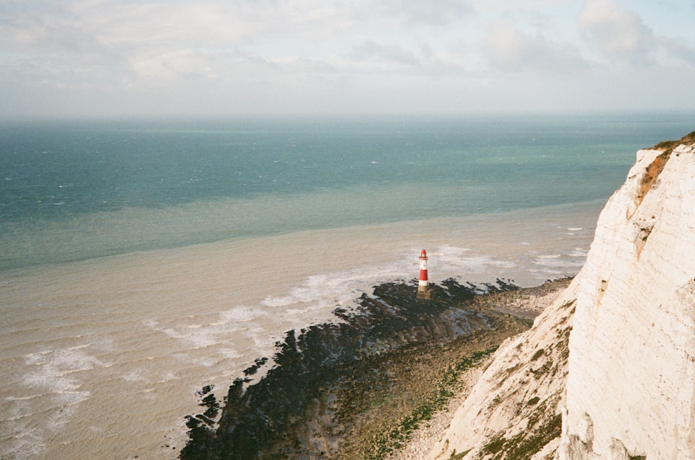 a red and white lighthouse sitting on top of a cliff