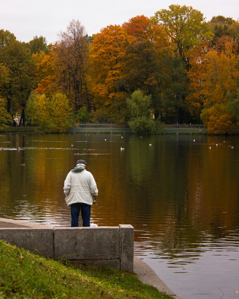 a man is standing on a ledge looking at the water