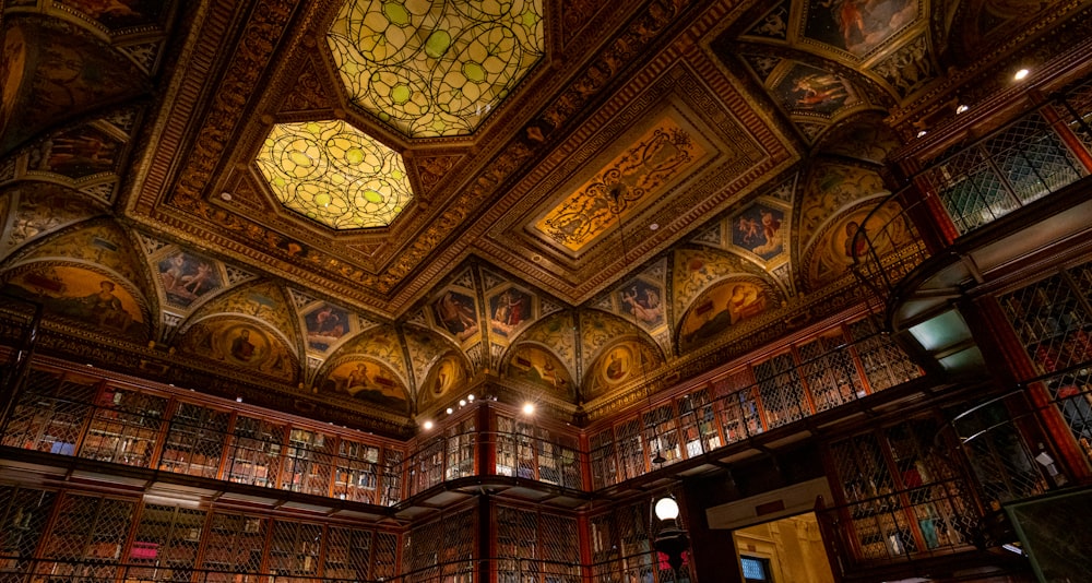 a library filled with lots of books under a stained glass ceiling