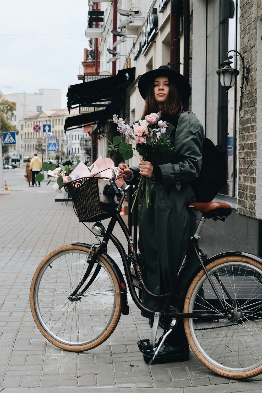 a woman standing next to a bicycle holding flowers