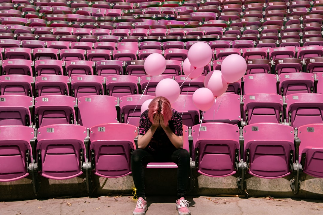 a person sitting on a bench in front of a bunch of pink chairs,