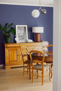 A dining area with a sleek wooden table, minimalist lighting, and a plush rug in deep navy tones.