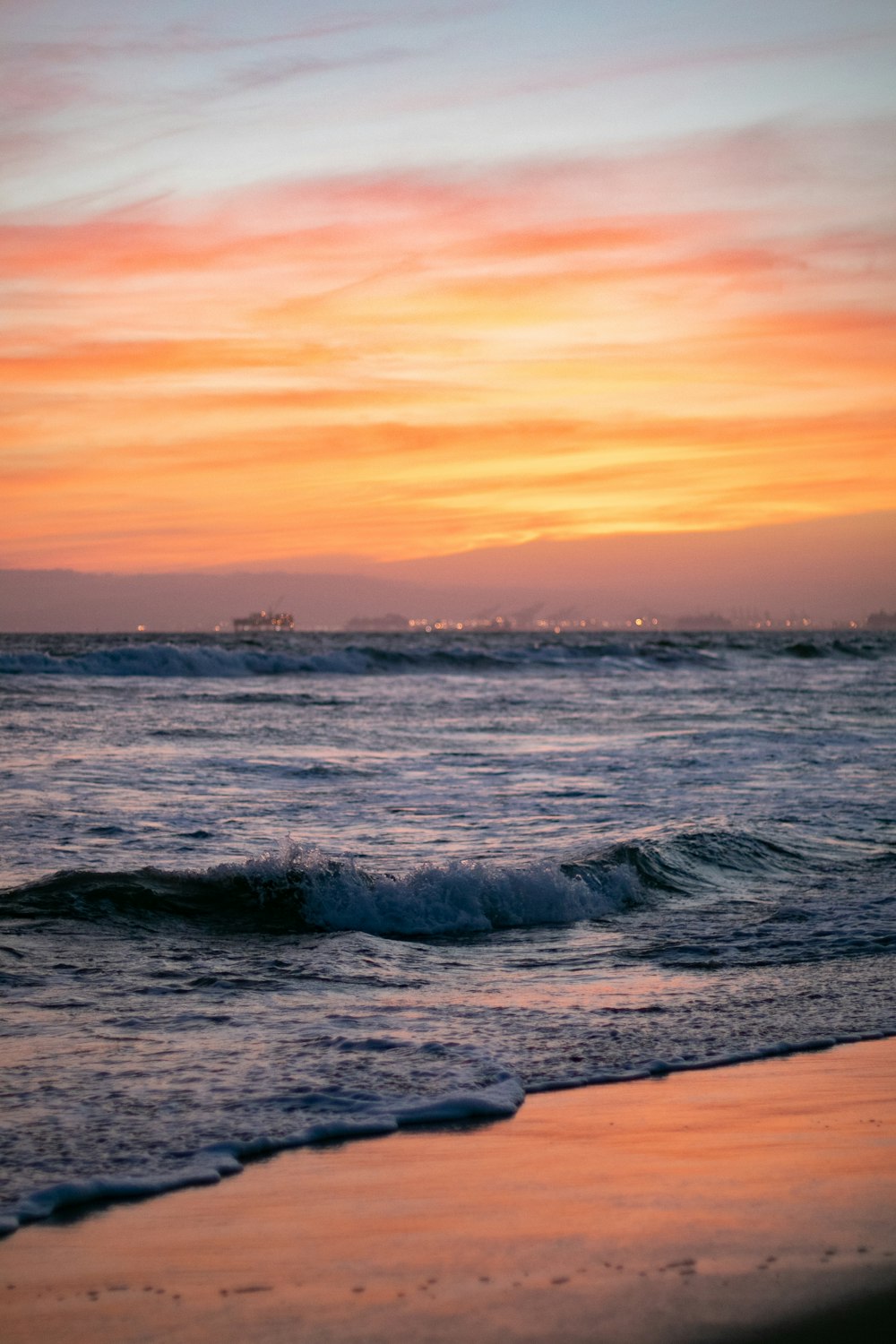 a sunset over the ocean with waves coming in