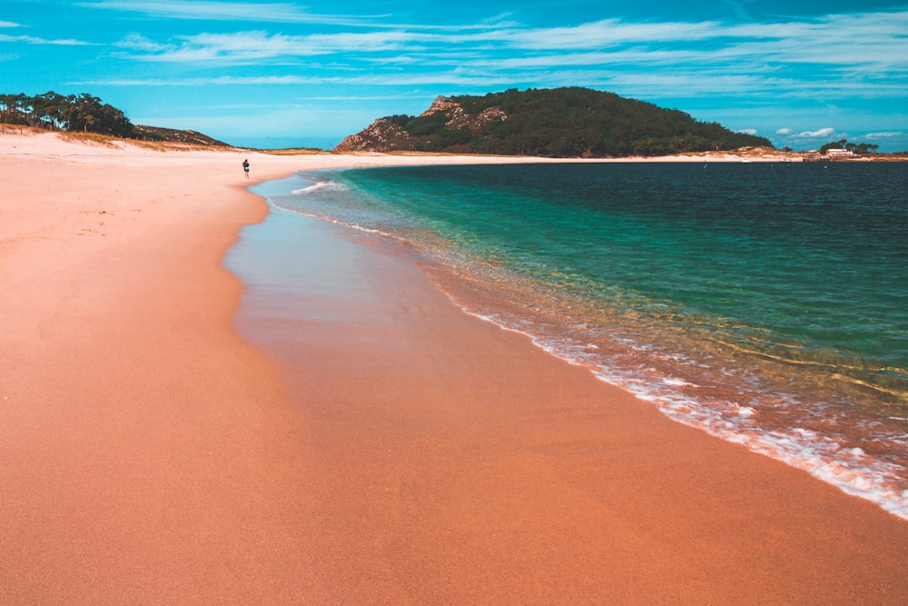 a person walking along a beach next to the ocean