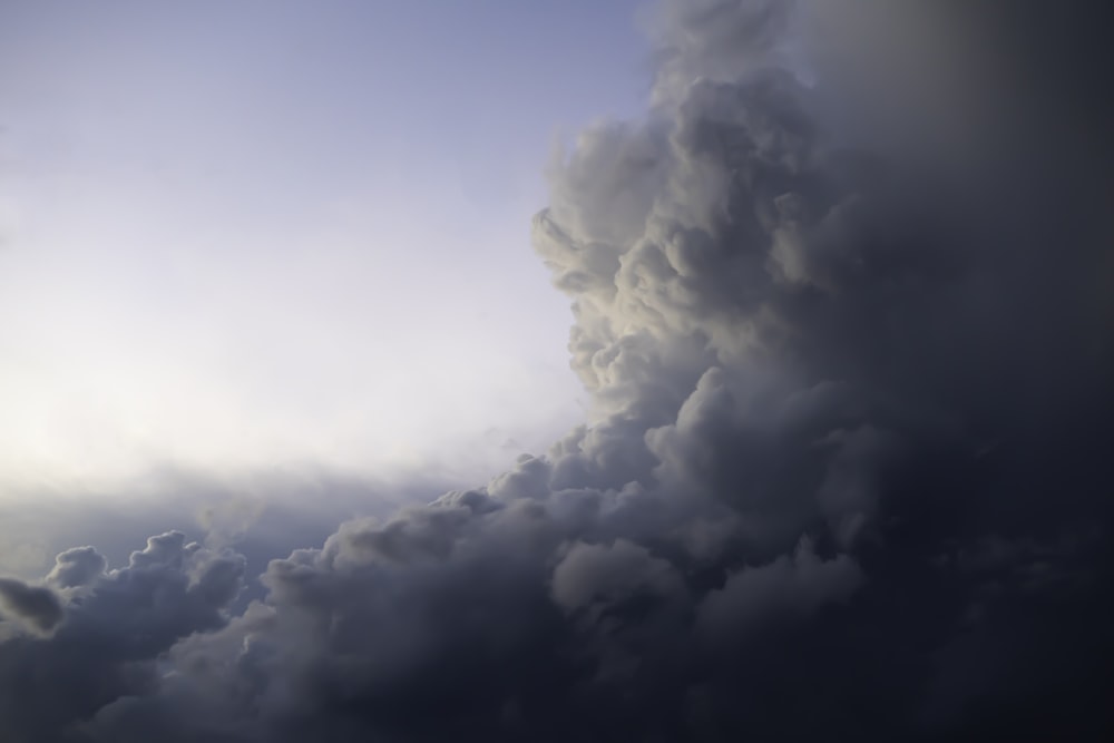 a plane flying through a cloudy blue sky