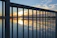 Close-up of a sleek custom metal railing with warm sunset lighting.