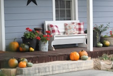 a porch with pumpkins and flowers on the steps