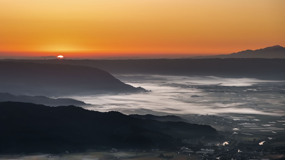 the sun is setting over a mountain range