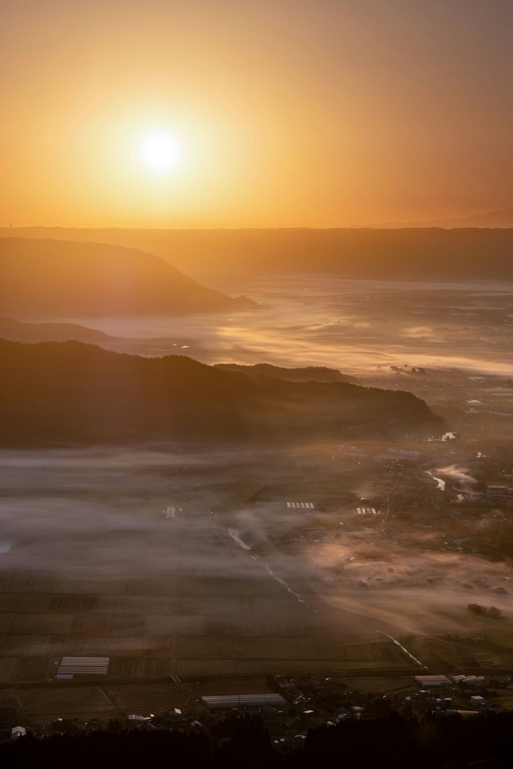 the sun is setting over a valley with fog