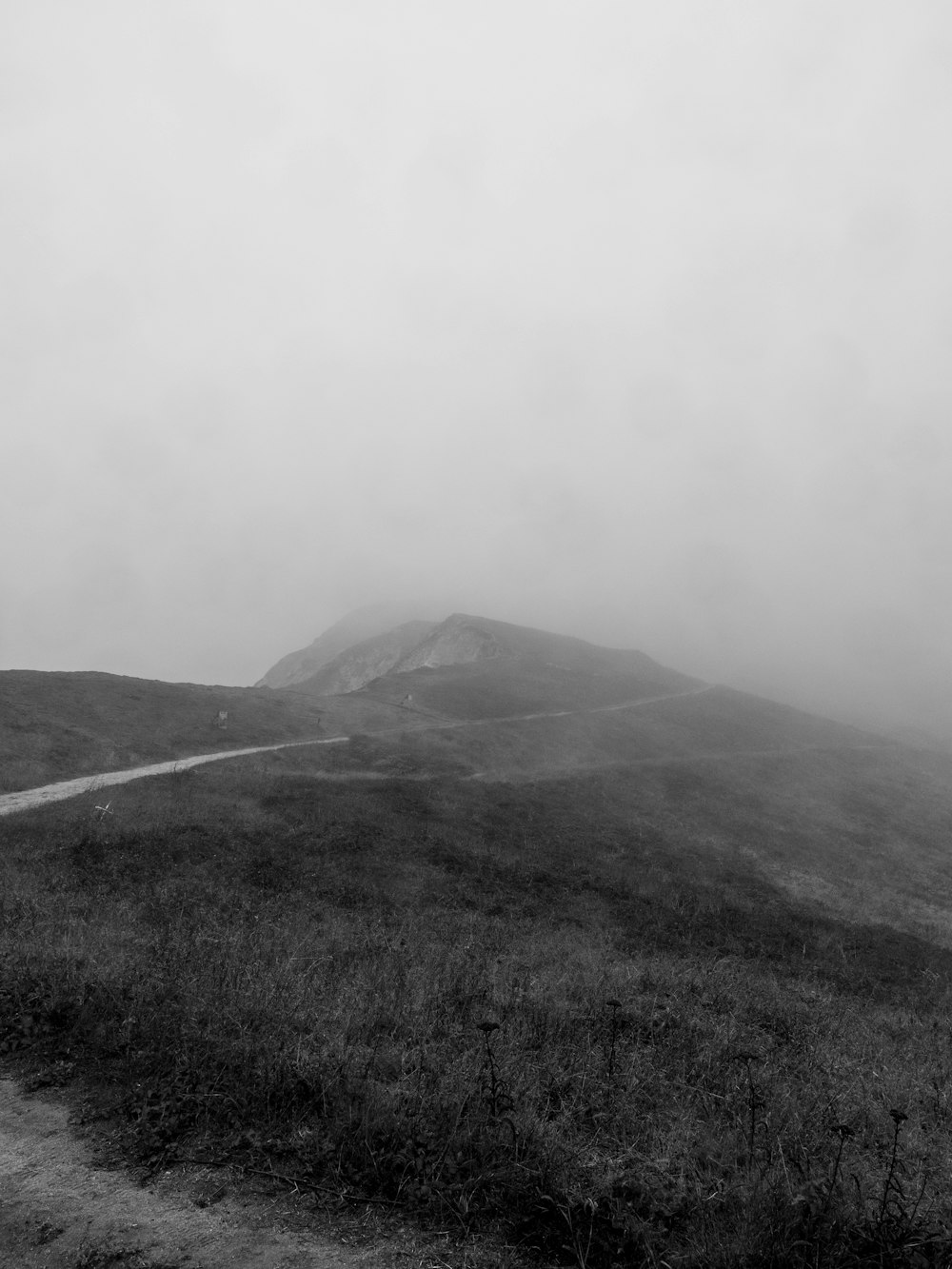 a black and white photo of a foggy mountain