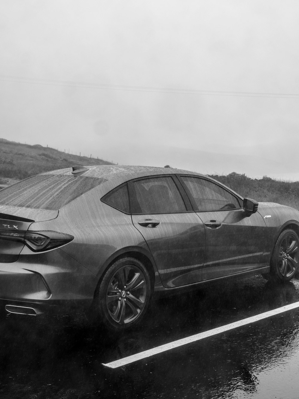 a black and white photo of a car in the rain