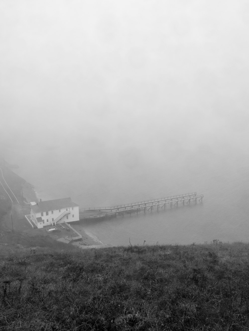 a black and white photo of a foggy pier