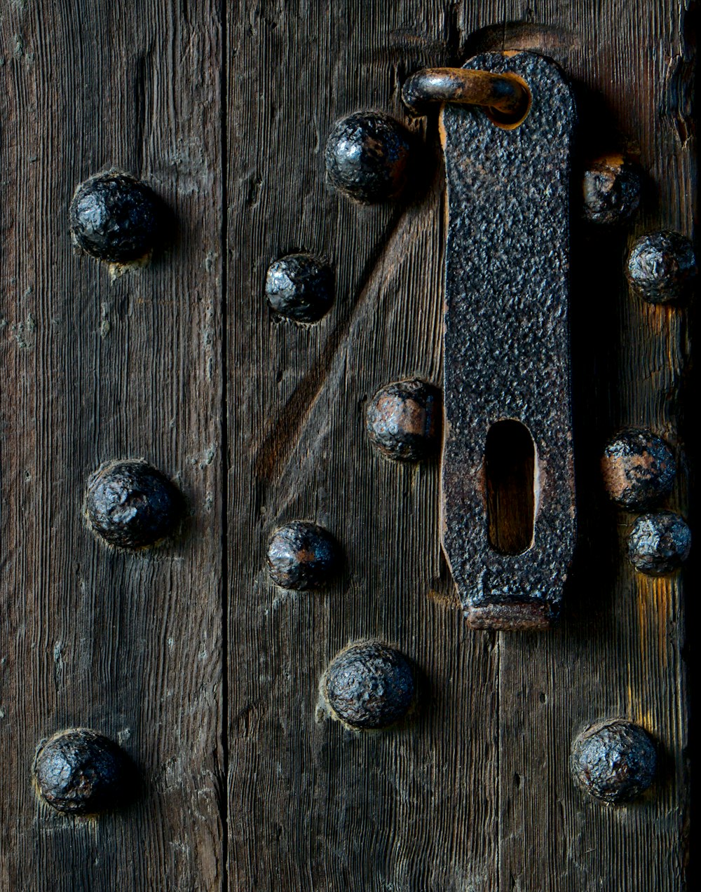 una manija de puerta en una puerta de madera rodeada de tuercas