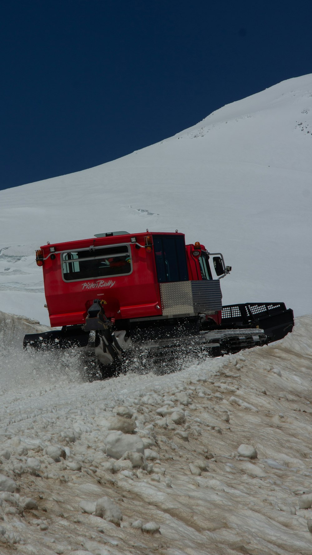 a red truck driving down a snow covered slope