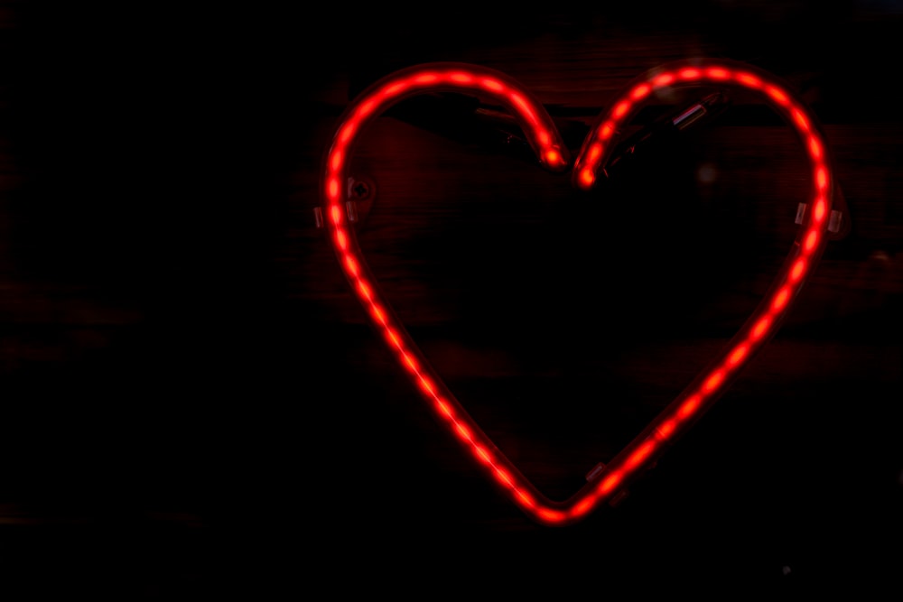 a heart shaped neon sign in the dark